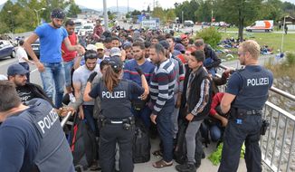 German police talk to the refugees on Austrian territory after they stopped them on a bridge at the border between Austria and Germany in Salzburg, Thursday, Sept. 17, 2015. (AP Photo/Kerstin Joensson)