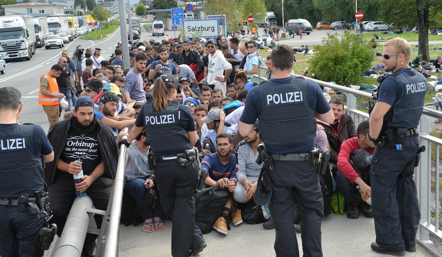 Refugees sit on a bridge after police stopped them at the border between Austria and Germany in Salzburg, Austria, Thursday, Sept. 17, 2015. (AP Photo/Kerstin Joensson)