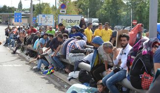 Refugees rest on the roadside after police stopped them near the border between Austria and Germany, in Salzburg, Austria, Thursday, Sept. 17, 2015. (AP Photo/Kerstin Joensson)
