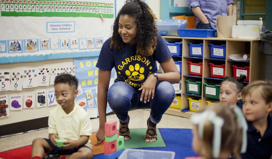 In this photo taken Aug. 28, 2015, Epernay Kyles, center, Pre-K teacher at Garrison Elementary in the Logan Circle neighborhood in Northwest Washington, meets with her students on the first day of classes. Millions of children are heading back to school after summer vacation. Many are excited, some anxious, and millions are still waiting for the results of the new tests they took last spring aligned to the Common Core academic standards. (AP Photo/Pablo Martinez Monsivais)