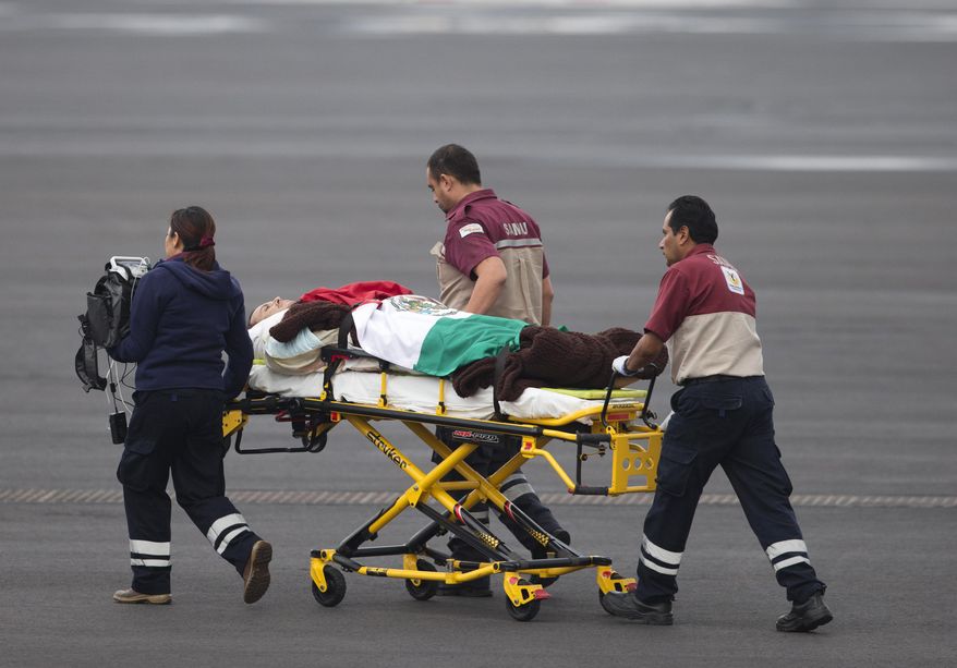 A Mexican man wounded in an attack by the Egyptian army while traveling in Egypt, is draped in a Mexican flag as he's transferred from the return flight to a waiting helicopter at the presidential hangar of Benito Juarez International Airport in Mexico City, Friday, Sept. 18, 2015. Eight other Mexicans died Sunday when Egyptian forces hunting militants mistakenly attacked their convoy in the western desert. (AP Photo/Rebecca Blackwell)
