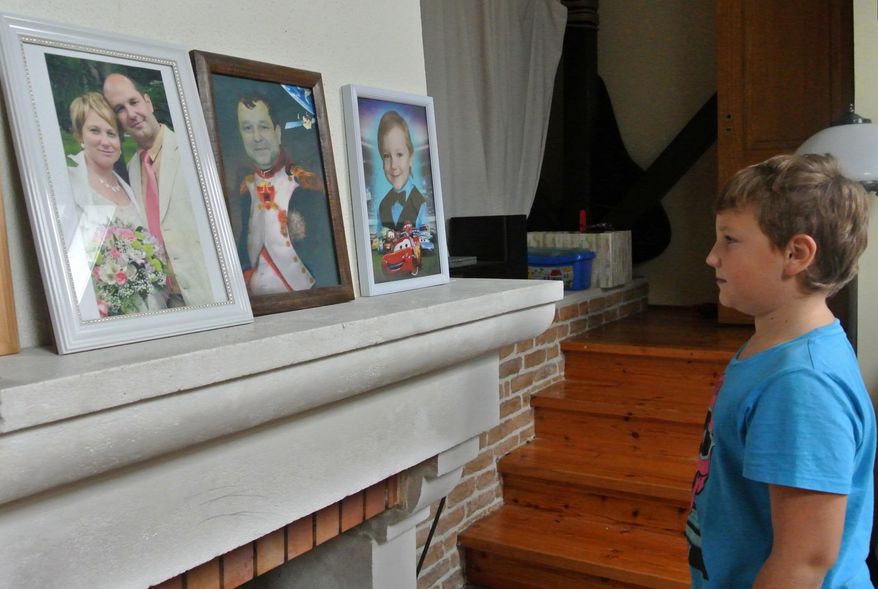 In this Friday, Sept. 4, 2015 photo Anton Kravtsov looks at a photo of his parents Alla and Gennady, at home in northern Moscow. His father, a former intelligence employee Gennady Kravtsov, is on trial on treason charges for sending a cover letter to Sweden. The Russian government increasingly has portrayed any cooperation with foreign companies or nationals as a potential security threat, a throwback to Soviet times when any contact with foreigners aroused suspicion. (AP Photo/Nataliya Vasilyeva)