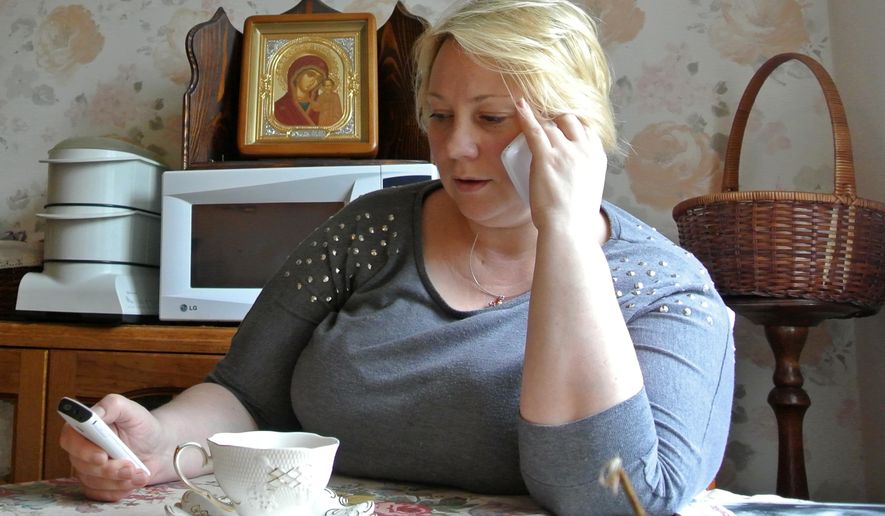 In this Friday, Sept. 4, 2015 photo Alla Kravtsova speaks on a phone at her home in northern Moscow. Kravtsova's husband, a former intelligence employee Gennady Kravtsov, is on trial on treason charges for sending a cover letter to Sweden. The Russian government increasingly has portrayed any cooperation with foreign companies or nationals as a potential security threat, a throwback to Soviet times when any contact with foreigners aroused suspicion. (AP Photo/Nataliya Vasilyeva)