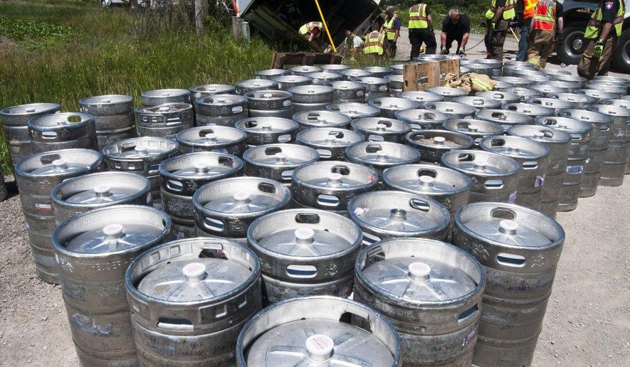 Firefighters remove kegs of beer after a semi-trailer tipped over on Fisher Road in Monitor Township on Friday, June 19, 2015. All barrels remained inside the truck after the accident and the driver was not hurt. (Nicole Hester/The Bay City Times via AP) LOCAL TELEVISION OUT