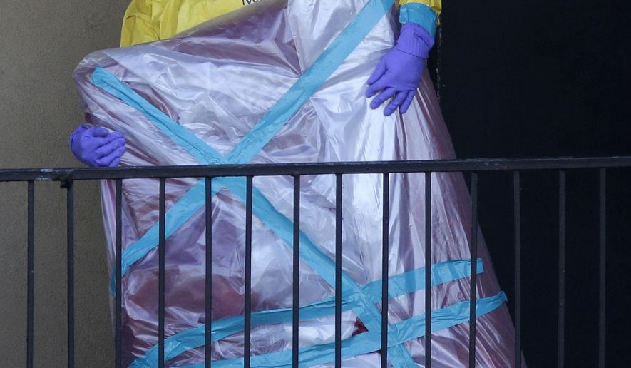 FILE - In this Oct. 6, 2014, file photo, a hazardous material cleaner removes a wrapped item from the Dallas apartment where Thomas Eric Duncan, the Ebola patient who traveled from Liberia to Dallas, stayed. Most people will experience at least one wrong or delayed diagnosis in their lifetime, concludes an alarming report that calls diagnostic errors a blind spot in modern medicine that can cause devastating consequences. (AP Photo/LM Otero, File)
