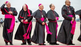 Clergy brace for the wind as they stand along the red carpet on the tarmac at Andrews Air Force Base, Md., Tuesday, Sept. 22, 2015, as the plane carrying Pope Francis arrives. (AP Photo/Andrew Harnik)