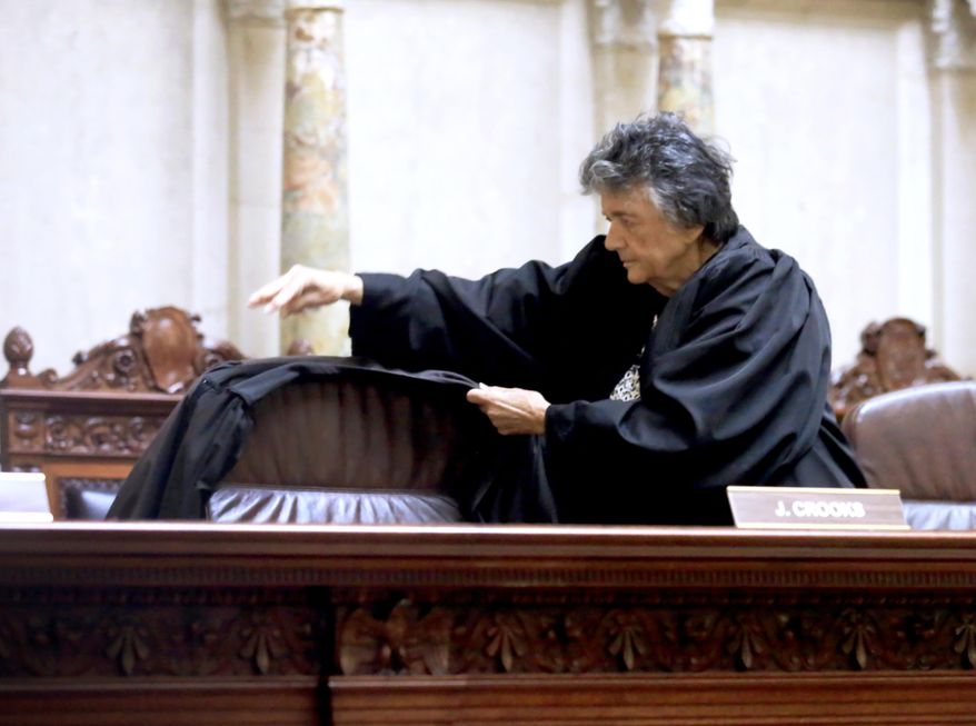 Wisconsin Supreme Court Justice Shirley Abrahamson places a judicial robe on the chair of the late Justice N. Patrick Crooks following a moment of silence in the court in the Wisconsin State Capitol in Madison, Wis. Tuesday, Sept. 22, 2015. Crooks died unexpectedly in his chambers on Monday afternoon. (John Hart/Wisconsin State Journal via AP) MANDATORY CREDIT
