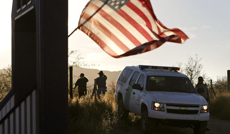 An American flag on a nearby resident&#39;s home waves in the breeze on Dec. 15, 2010, near a U.S. Border Patrol truck blocking the road leading to a search area near where agent Brian Terry, 40, was killed northwest of Nogales, Ariz. (Arizona Daily Star via Associated Press)