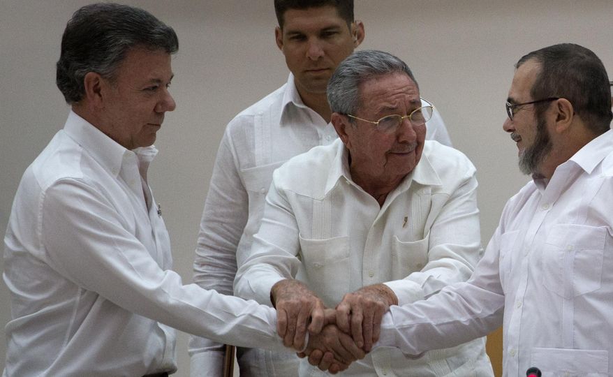 Cuba's President Raul Castro, center, encourages Colombian President Juan Manuel Santos, left, and Commander the Revolutionary Armed Forces of Colombia or FARC, Timoleon Jimenez to shake hands, in Havana, Cuba, Wednesday, Sept. 23, 2015. In a joint statement, Santos and the FARC said they have overcome the last significant obstacle to a peace deal by settling on a formula to compensate victims and punish belligerents for human rights abuses. (AP Photo/Desmond Boylan)