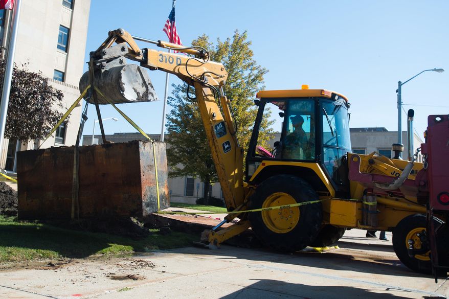 In this photo taken Wednesday, Sept. 23, 2015, Tim Fedek, Bay County Building and Grounds, uses a backhoe to lift a 50-year-old time capsule onto a truck at Bay County Building's southwest lawn in Bay City, Mich. (Yfat Yossifor/The Bay City Times via AP) LOCAL TELEVISION OUT; LOCAL INTERNET OUT; MANDATORY CREDIT