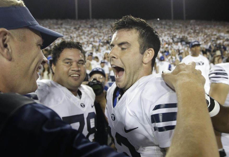 FILE - This Sept. 12, 2015, file photo, shows BYU quarterback Tanner Mangum, right, celebrating on the sidelines late in the second half of an NCAA college football game against Boise State in Provo, Utah. No. 22 BYU moved into the rankings by beating Nebraska and then-No. 20 Boise State with last-minute, come-from-behind efforts. (AP Photo/Rick Bowmer, File)