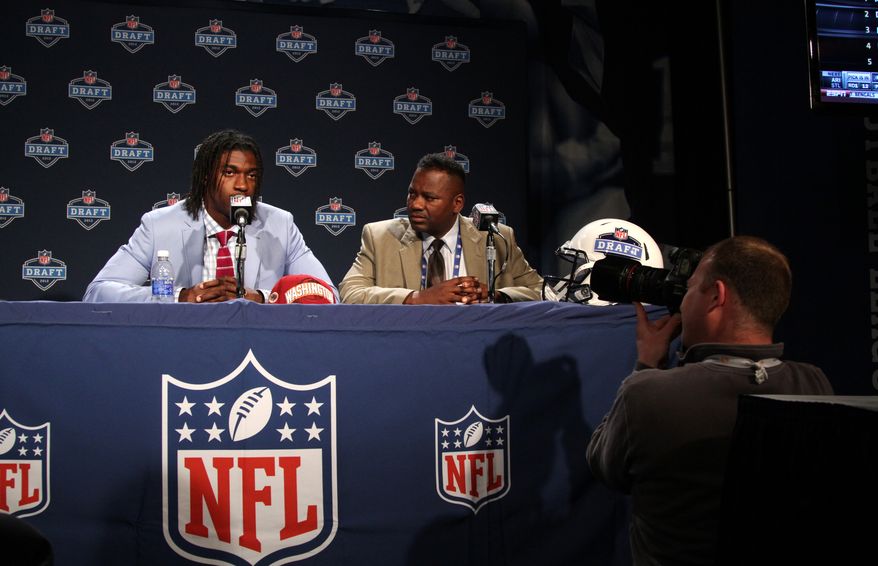 Quarterback Robert Griffin III, left, is joined by his father Robert Griffin Jr. as he speaks to reporters after he was selected as the second pick overall by the Washington Redskins in the first round of the NFL football draft at Radio City Music Hall, Thursday, April 26, 2012, in New York. (AP Photo/Mary Altaffer)