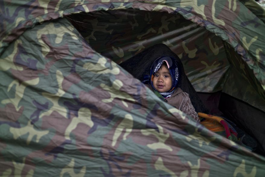 Afghan refugee Asma Mohammed, 2, looks out a tent where she and her family spent the night at a collection point in the truck parking lot of the former border station on the Austrian side of the Hungarian-Austrian border near Nickelsdorf, Austria, Friday, Sept. 25, 2015. Deeply divided European Union leaders held an emergency summit to seek long-term responses to the continent's ballooning crisis of refugees and migrants, a historic challenge EU President Donald Tusk said the bloc has failed dismally to meet. (AP Photo/Muhammed Muheisen)