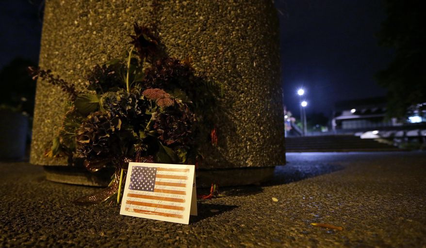 A plant arrangement and a card are seen near the main entrance to North Seattle College, Thursday, Sept. 24, 2015, after multiple students in the college's international program were killed when the charter bus they were riding in to an orientation event was hit by a Ride the Ducks tourist vehicle in Seattle. (AP Photo/Ted S. Warren)