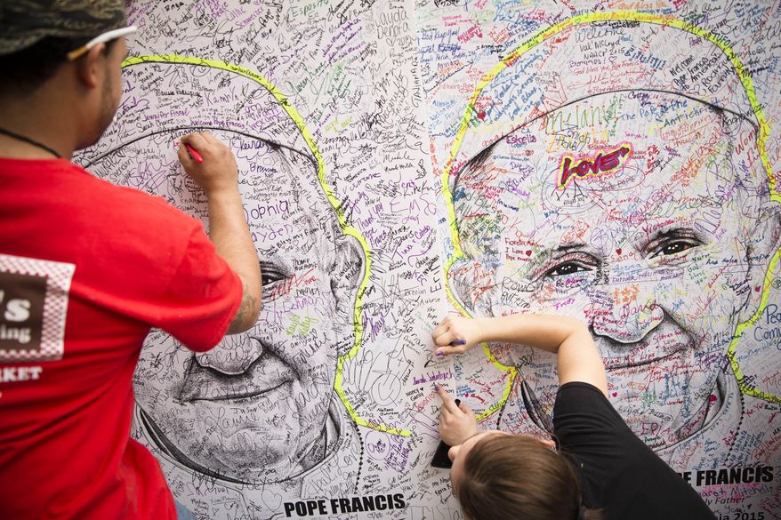 Pedestrians write messages and signatures on the likeness of Pope Francis, Friday, Sept. 25, 2015, in downtown Philadelphia. The pope wraps up his U.S. visit this weekend in Philadelphia, where he speaks in front of Independence Hall and celebrates Mass on the Benjamin Franklin Parkway to close out a big rally on Catholic families. (AP Photo/John Minchillo)