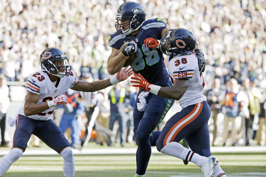 Seattle Seahawks tight end Jimmy Graham, center, gets through Chicago Bears free safety Adrian Amos, right, and cornerback Kyle Fuller, left, as he runs for a touchdown after a reception against the Chicago Bears in the second half of an NFL football game, Sunday, Sept. 27, 2015, in Seattle. (AP Photo/Elaine Thompson)