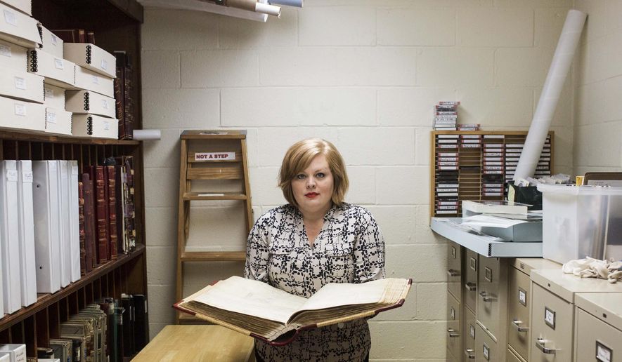 In this Sept. 18, 2015 photo, Kim McCollum, executive director at Elmwood Cemetery, holds open the large Turley Lot Book that contains the location and names of the many children that are buried at the Elmwood Cemetery in Memphis, Tenn. The babies who passed away in the care of the infamous Tennessee Children's Home Society, where operator Georgia Tann ran a highly organized and lucrative baby-selling network from 1923 until her death in 1950. (Brad Vest/The Commercial Appeal via AP) MANDATORY CREDIT