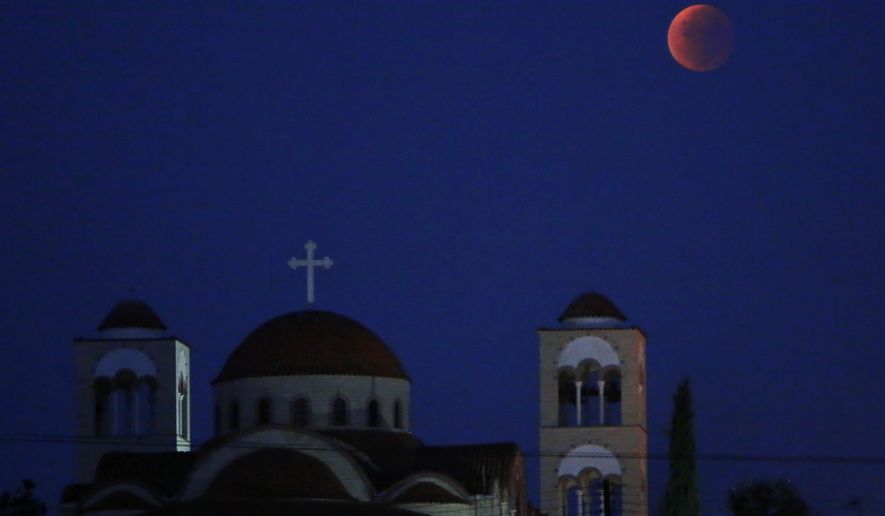 A “blood moon” casts its glow over a Christian Orthodox church in Anthoupolis, a suburb of Nicosia in the early hours of Monday, Sept. 28, 2015. A lunar eclipse has given the moon a red tint and makes it appear larger than usual. The rare confluence of an eclipse and supermoon won’t happen again for 18 years. (AP Photo/Petros Karadjias)