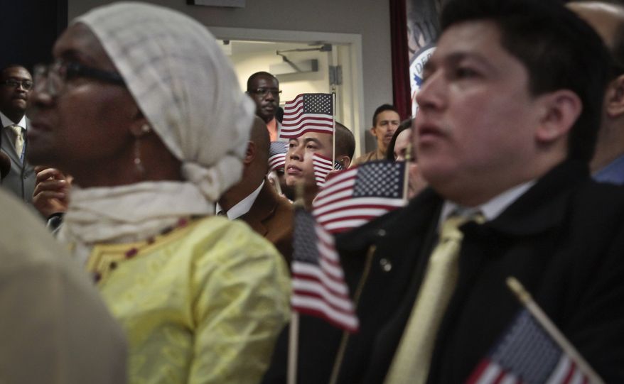 Immigrants hold miniature U.S. flags as they listen to a video broadcast from President Barack Obama during a naturalization ceremony attended by Mayor Michael Bloomberg in New York, in this Dec. 18, 2013, file photo. (AP Photo/Bebeto Matthews, File)