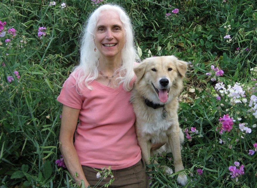 In this undated photo provided by Dr. Pamela Fisher shows, Pamela Fisher and her best friend, Lili, pose for a selfie in a field of flowers in Canton, Ohio. Fisher started a campaign nearly four years ago called Rescue Animal MP3 Project. Musicians donated 30 hours of music that stops dogs from barking and de-stresses and relaxes dog and cats. She has now provided over 1,100 MP3 players to shelters across the country. She was installing a player in a shelter in Akron, Ohio, when a glance from Lili rather than a sound won her over. (Dr. Pamela Fisher via AP)