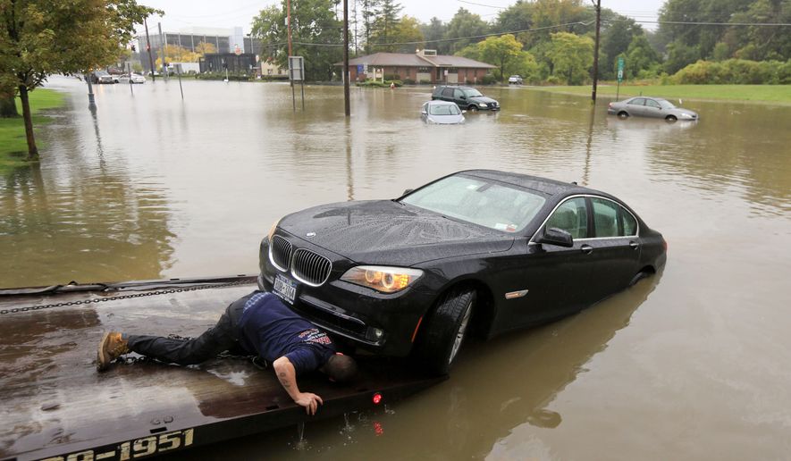 A worker prepares to tow a stranded vehicle from a flooded road on Wednesday, Sept. 30, 2015, in Guilderland, N.Y. The National Weather Service has issued flood watches for much of the eastern half of upstate New York as a storm dumps more than two inches of rain across the region. (AP Photo/Mike Groll)