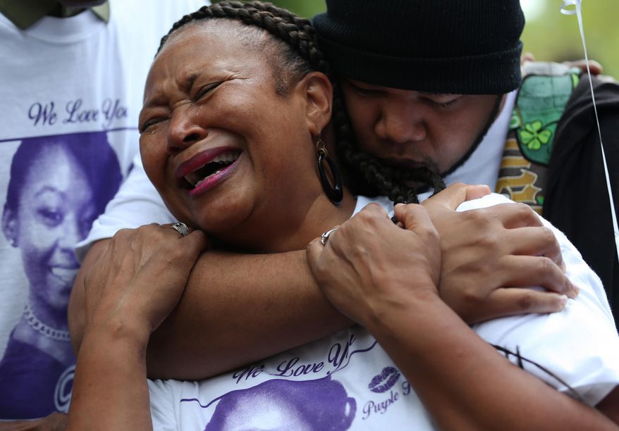 Nia Imani grieves for her daughter Tiara Bogan Jones as her son Robert Bogan comforts her Thursday, Oct. 1, 2015, during a vigil near where the mother of two was shot and killed in Atlanta. She was killed Saturday when shots were fired from another vehicle at an SUV, which hit a tree and flipped over. (Ben Gray/Atlanta Journal-Constitution via AP) MARIETTA DAILY OUT; GWINNETT DAILY POST OUT; LOCAL TELEVISION OUT; WXIA-TV OUT; WGCL-TV OUT; MANDATORY CREDIT