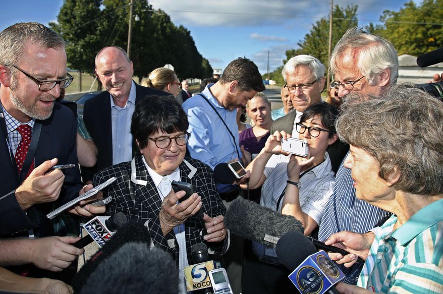 Death penalty opponent Sister Helen Prejean, center, tries to put death row inmate Richard Glossip on speaker phone outside the Oklahoma State Penitentiary, following a stay in his scheduled execution, in McAlester, Okla., Wednesday, Sept. 30, 2015. (AP Photo/Sue Ogrocki)