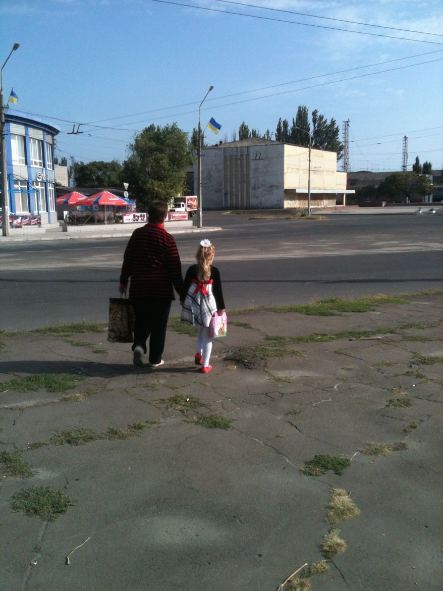 A babushka escorts her grandchild across the street in Mariupol, Ukraine. (Photo by L. Todd Wood)