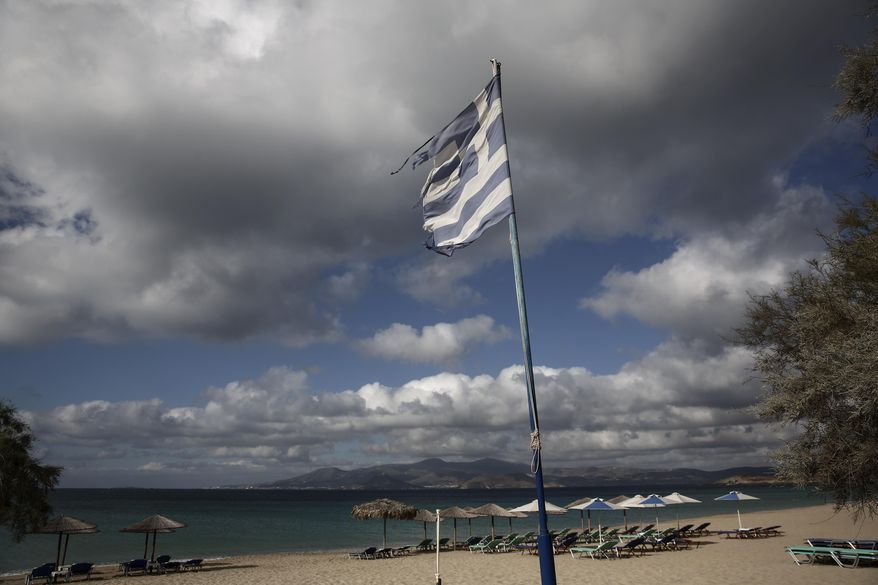 A Greek tattered flag flutters at Agios Prokopios beach on the Greek Aegean island of Naxos, Greece, Oct 1, 2015. For decades, Greece’s Aegean islands enjoyed a value added tax rate 30 percent lower than the rest of the country, to offset increased transportation costs and prevent their dwindling permanent populations from deserting them altogether, but now the islands are losing that benefit as part of creditor-demanded reforms for Greece's third international bailout. (AP Photo/Yorgos Karahalis)