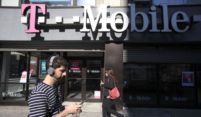 A man uses a cellphone as he passes a T-Mobile store in New York in this Sept. 12, 2012, file photo. (AP Photo/Mark Lennihan, File)