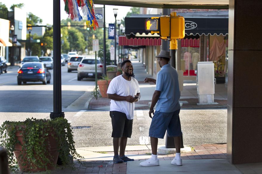 FOR RELEASE SUNDAY, OCTOBER 4, 2015, AT 12:01 A.M. EDT.- This photo taken July 24, 2015, shows Wayne McPhatter, left, chatting with Pernell Carthens on Main Street in Laurinburg, N.C. The Laurinburg Downtown Revitalization Corp. has invested $165,000 to freshen up the store fronts downtown and recruit new businesses. After power washing and fresh paint, new awning were installed. (Robert Willett/The News & Observer via AP)
