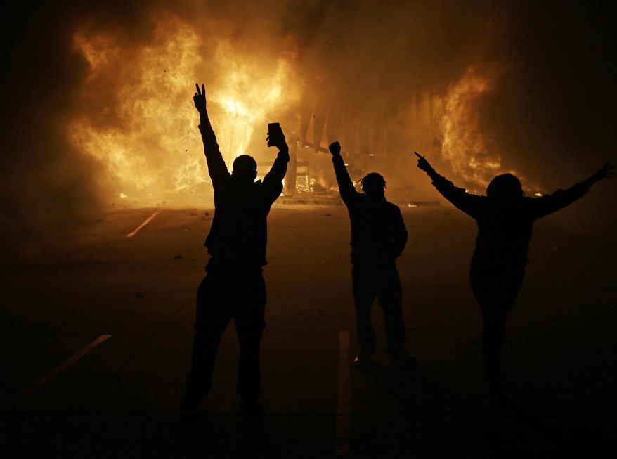 FILE - In this Nov. 25, 2014, file photo, people watch as stores burn in Ferguson, Mo., after a grand jury decided not to indict Ferguson police Officer Darren Wilson in the death of Michael Brown, the unarmed, black 18-year-old whose fatal shooting sparked sometimes violent protests. The U.S. Department of Justice on Friday, Oct. 2, 2015, will release the findings of the last of its third and final review stemming from the unrest in Ferguson. (AP Photo/David Goldman, File)