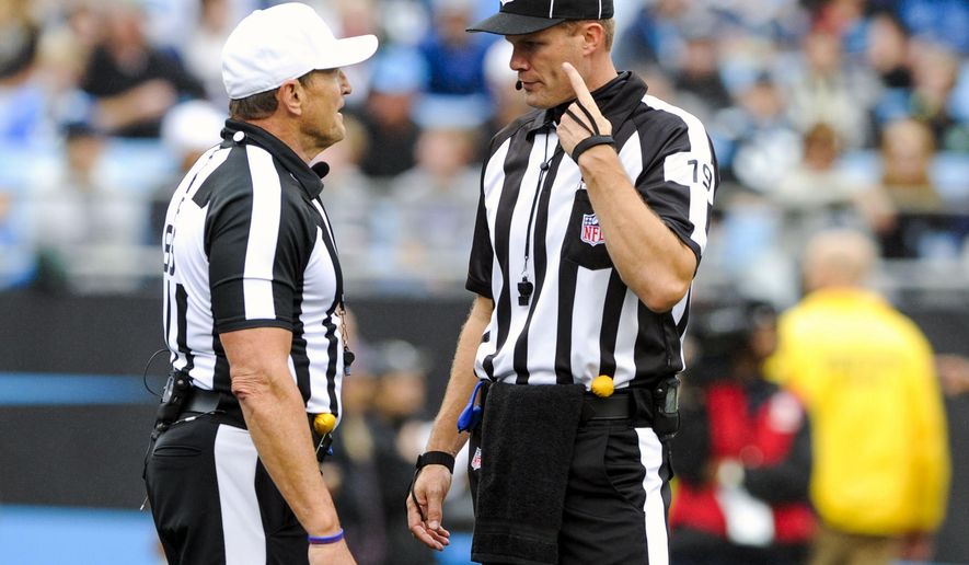 FILE - In this Sept. 27, 2015, file photo, referee Ed Hochuli (85) talks with umpire Clay Martin during an NFL football game between the Carolina Panthers and the New Orleans Saints in Charlotte, N.C. Three games into the NFL season, yellow flags are flying. And if it seems as if it’s been popping up so far this season more than ever, well, it has. (AP Photo/Mike McCarn, File)