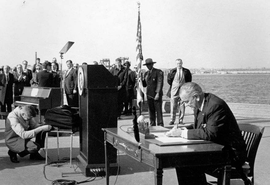 FILE - In this Oct. 3, 1965, file photo President Lyndon B. Johnson sits at his desk on Liberty Island in New York Harbor as he signs a new immigration bill. It was presented as a symbolic move - President Lyndon Johnson on Liberty Island, signing an immigration bill that gave people from every country in the world an equal chance to come to America. Fifty years later, there’s little that hasn’t been changed as a result of the Hart-Celler Act that Johnson signed on Oct. 3, 1965. A country that was almost entirely native-born in 1965 has a significant foreign-born population; demographic diversity has spread to every region, expanding a black-and-white racial paradigm into a multi-colored one. Americans have gleefully adopted musical genres and foods that have immigrant origins, while remaining conflicted and uneasy politically over who’s here, legally and not. (AP Photo, File)