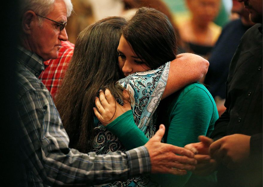 Lacey Scroggins, a survivor of the shooting at Umpqua Community College (right), embraces another woman during a church service Sunday in Roseburg, Oregon. Despite President Obama's impassioned speech, no change on gun policy is expected. (Associated Press photographs)