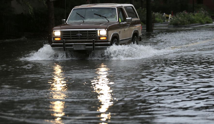 A motorist drives his truck through a flooded street in Charleston, S.C., Sunday, Oct. 4, 2015. President Barack Obama declared a state of emergency in South Carolina and ordered federal aid to bolster state and local efforts as flood warnings remained in effect for many parts of the East Coast through Sunday. (AP Photo/Chuck Burton)
