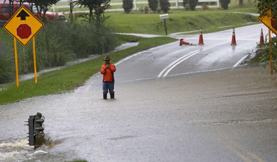 A man stands in floodwaters covering a road in Florence, S.C., Sunday, Oct. 4, 2015, as heavy rains continue to cause flooding in many parts of the state. The rainstorm drenching the U.S. East Coast brought more misery Sunday to South Carolina, cutting power to thousands, forcing hundreds of water rescues and closing many roads because of floodwaters. (AP Photo/Gerry Broome)