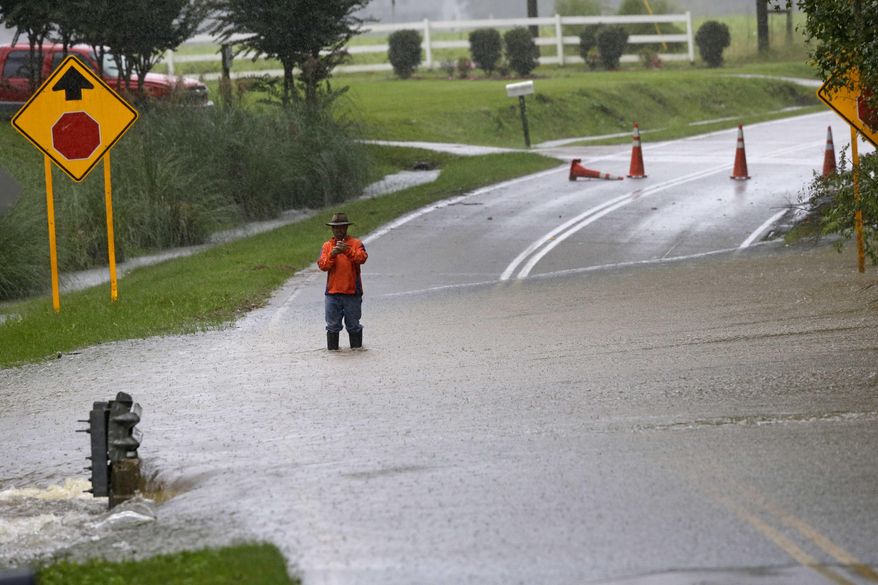 A man stands in floodwaters covering a road in Florence, S.C., Sunday, Oct. 4, 2015, as heavy rains continue to cause flooding in many parts of the state. The rainstorm drenching the U.S. East Coast brought more misery Sunday to South Carolina, cutting power to thousands, forcing hundreds of water rescues and closing many roads because of floodwaters. (AP Photo/Gerry Broome)