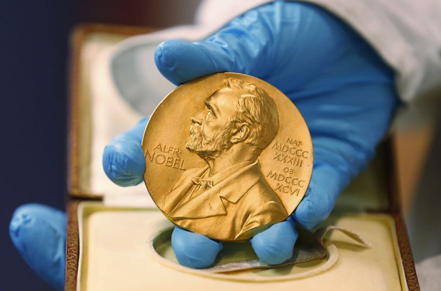 In this file photo dated Friday, April 17, 2015, a national library employee shows the gold Nobel Prize medal awarded to the late novelist Gabriel Garcia Marquez, in Bogota, Colombia. The beginning of October 2015 means Nobel Prize time, when committees in Stockholm and Oslo announce the winners of what many consider the most prestigious awards in the world, each worth some 8 million Swedish kronor (U.S. $960,000) presented to the worthy recipients with a diploma and a gold medal. (AP Photo/Fernando Vergara, FILE)