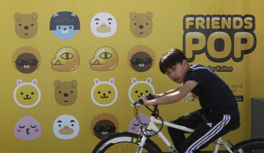 In this Sunday, Oct. 4, 2015, photo, a boy cycles by a billboard advertising Kakao Talk, a popular mobile messenger app, during the Busan International Film Festival at Busan Cinema Center in Busan, South Korea. Asia's largest film festival is trying to ensure that message-addicted smartphone users don't look at the chat app during screenings. The 20th Busan International Film Festival is showing a short clip before every movie with instructions not to check Kakao Talk messages because the glowing screen can disturb others. (AP Photo/Ahn Young-joon)