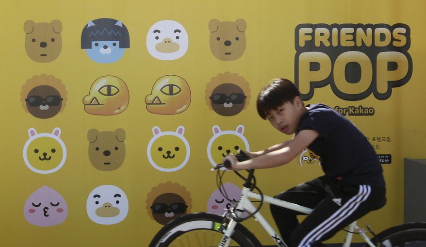 In this Sunday, Oct. 4, 2015, photo, a boy cycles by a billboard advertising Kakao Talk, a popular mobile messenger app, during the Busan International Film Festival at Busan Cinema Center in Busan, South Korea. Asia's largest film festival is trying to ensure that message-addicted smartphone users don't look at the chat app during screenings. The 20th Busan International Film Festival is showing a short clip before every movie with instructions not to check Kakao Talk messages because the glowing screen can disturb others. (AP Photo/Ahn Young-joon)