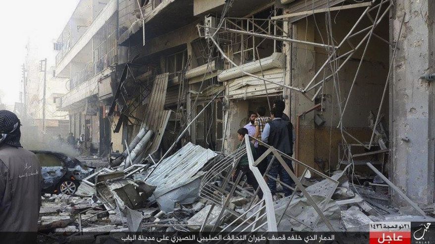 In this Monday, Oct. 5, 2015 photo released by the Rased News Network, a Facebook account affiliated with Islamic State militants, which has been authenticated based on its contents and other AP reporting, people gather at the site of an airstrike in Al-Bab on the outskirts of Aleppo, Syria. The Britain-based Syrian Observatory for Human rights said warplanes believed to be Russian have targeted the northern town of Al-Bab that is a stronghold of the Islamic State group. The Arabic at the bottom reads, "The destruction that was caused by airstrikes of the Crusader-Alawite coalition on the town of Al-Bab." (Rased News Network via AP)
