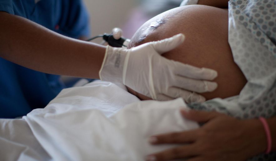 In this July 25, 2012 file photo, a pregnant woman is examined as she waits to give birth at a public hospital in Rio de Janeiro. (AP Photo/Felipe Dana, File)
