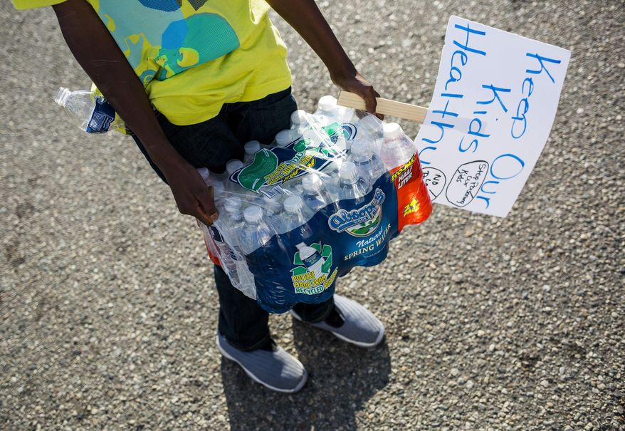 Community leaders pass out cases of bottled water to Flint residents on Wednesday, Oct. 7, 2015, in downtown Flint, Mich. The bottle delivery was made possible by donations raised through a group's GoFundMe.com page called "Bottles for Babies." (Danny Miller /The Flint Journal-MLive.com via AP) LOCAL TELEVISION OUT; LOCAL INTERNET OUT; MANDATORY CREDIT