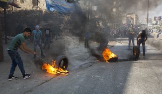 Palestinians burn tires during clashes with Israeli troops at a checkpoint between Jerusalem and the West Bank city of Ramallah. (Associated Press/File)