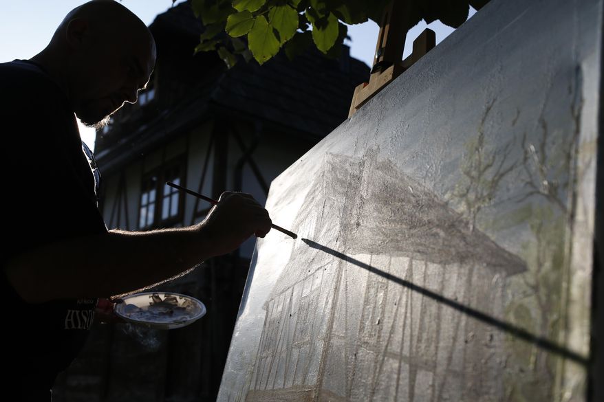 In this photo taken on Saturday, Oct. 3, 2015, amateur painter Safet Berber puts final touches to a painting during a weekend gathering of artist in the village of Dzafici, 100 kms north of Sarajevo. To allow people a break from their busy lives, Bosnian man Rasim Hamidovic, 60, is organising weekend gatherings of various artists in his home in Dzafici to remind them and other villagers of the old way of life in harmony with nature. (AP Photo/Amel Emric)