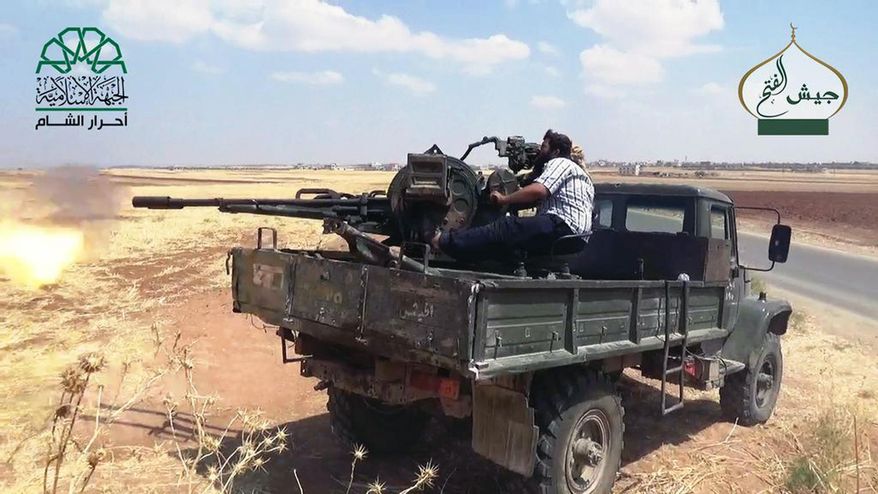 In this image posted on the Twitter page of Ahrar al-Sham on Aug. 8, 2015, a fighter from the al-Qaida-linked Ahrar al-Sham fires his weapon against pro-government fighters in the northwestern village of Foua in Idlib province, Syria. In an effort to improve its image in the West, the group's self-styled foreign affairs director has written opinion pieces in the Washington Post and Britain's Daily Telegraph to present his group as a moderate alternative and potential partner for Western governments. (Ahrar al-Sham Twitter page via AP)