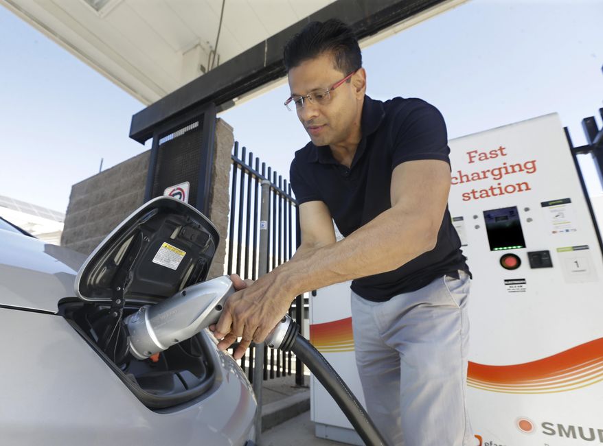In this photo taken Thursday, Sept. 17, 2015, Darshan Brahmbhatt, plugs a charger into his electric vehicle at the Sacramento Municipal Utility District charging station in Sacramento, Calif. Climate change legislation signed Wednesday, Oct. 7 by Gov. Jerry Brown calls for major utilities to compete as an alternative transportation fuel source by installing thousands of charging stations where people live, work and play. (AP Photo/Rich Pedroncelli)
