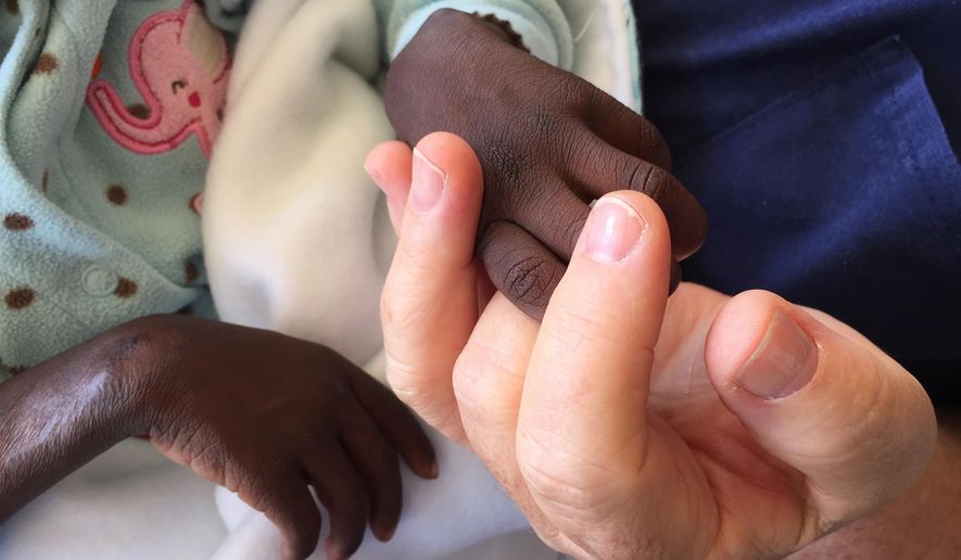 In this Sept. 15, 2015 photo, provided by the Lehigh Valley Hospice, the Hospice Director Jeannie Vogt holds a boy&#x27;s hand at Kimbilio Hospice in the village of Kipkaren in western Kenya, a facility funded by Living Room Ministries International. Three employees of Lehigh Valley Hospice traveled to Africa in September 2015 hoping to help and, perhaps, impart some of their knowledge. (Jeannie Vogt/Lehigh Valley Hospice via AP)