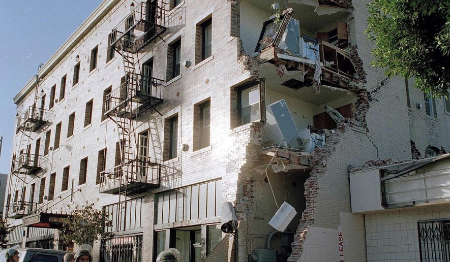 FILE - In this Jan. 18, 1994, file photo, California National Guardsman walk past a Hollywood apartment building damaged by a deadly earthquake in Los Angeles. The Los Angeles City Council is expected to pass a retrofitting law Friday, Oct. 9, 2015,  requiring costly upgrades of thousands of older wood and concrete apartment buildings that would be vulnerable to collapse in a major earthquake. (AP Photo/Kevork Djansezian, File)